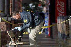 In this Jan. 10, 2011, file photo an F.B.I. agent writes down information as he looks around the area at a local Safeway in Tucson, Ariz., where Rep. Gabrielle Giffords, D-Ariz., was shot, two days after a mass shooting there left six dead.  A review of threat prosecutions by The Associated Press following last month's Arizona shootings, shows that it typically takes much more than posting warnings on obscure Internet sites, of the kind left by the defendant Jared Loughner in that attack, to lead authorities to act.  (AP Photo/Ross D. Franklin, File)