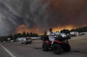 Robert Joseph, 64, rides his ATV as smoke plumes from the Wallow fire fill the sky in Luna, N.M., Monday, June 6, 2011. Firefighters worked furiously Monday to save a line of mountain communities in eastern Arizona from a gigantic blaze that has forced thousands of people from their homes and cast a smoky haze over states as far away as Iowa. (AP Photo/Jae C. Hong)