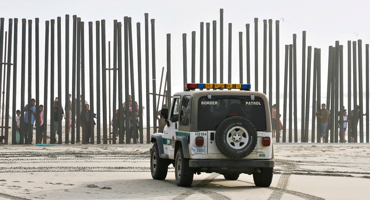 In this Jan. 18, 2009 file photo, a U.S. Border Patrol vehicle sits parked in front of a crowd of people peering through the U.S.-Mexico border fence at Border Field State Park in San Diego. At one time, before the enhanced border fence in the area, the San Diego area held the most popular routes for illegal immigrants heading into the U.S. (AP Photo/Denis Poroy)