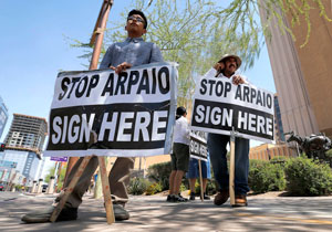 Simon Lopez, left, and Hiliaro Islas hold signs while trying to collect signatures in an effort to recall Maricopa County Sheriff Joe Arpaio, Wednesday, May 29, 2013 in downtown Phoenix. Organizers of a campaign aimed at ousting Arpaio face a deadline Thursday afternoon for handing signatures to force a recall election against the lawman. Recall organizers, who had trouble raising contributions and had to rely on volunteers rather than paid professionals to sign up supporters, face long odds in turning in more than 335,000 valid voter signatures. Arpaio critics are hoping a court ruling last week that Arpaio's office has racially profiled Latinos would draw out more supporters for their cause. (AP Photo/Matt York)