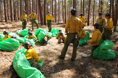 Phillip Maldonado, a squad leader with the Granite Mountain Hotshots, helps crew member learn the finer points of setting up emergency fire shelters. Training is key as the crew prepares for what’s expected to be a busy wildfire season. (Cronkite News Service photo by Connor Radnovich)