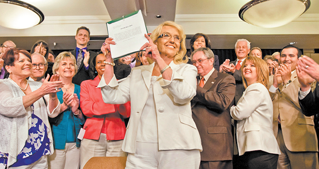 Arizona Gov. Jan Brewer holds up the contentious Medicaid expansion bill after signing it into law. (Photo by Evan Wyloge/Arizona Capitol Times)