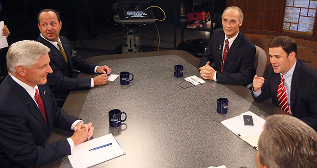 Television host moderator Ted Simons, bottom right, joins Arizona candidates for governor including Republican Doug Ducey, right, Libertarian Barry Hess, third from right, Americans Elect party candidate John Mealer, second from left, and Democrat Fred DuVal, left, as they chat prior to a televised debate Monday, Sept. 29, 2014, in Phoenix. (AP Photo/Ross D. Franklin)