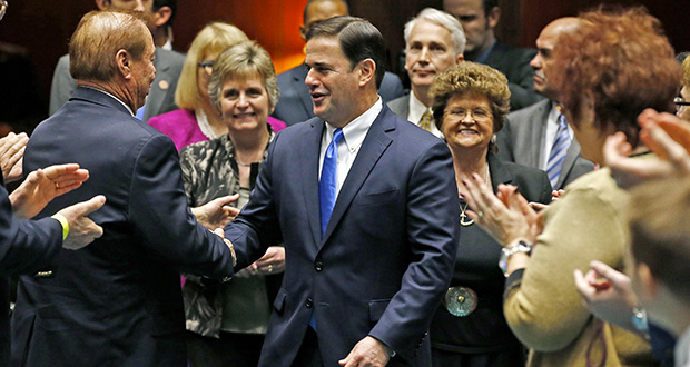 Arizona Republican Gov. Doug Ducey, center, shakes hands with state Sen. Frank Pratt, left, R-Casa Grande, as he arrives to give his State of the State Address, opening the Arizona state legislature Monday, Jan. 9, 2017, in Phoenix. (AP Photo/Ross D. Franklin)