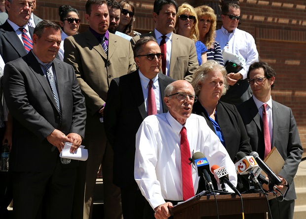 Plaintiffs in a lawsuit over school maintenance funding stand behind Arizona Center for Law in the Public Interest attorney Tim Hogan. Standing on the steps of Glendale Landmark Elementary School on Monday, Hogan argued the state is not living up to its constitutional obligations to properly fund school maintenance and construction, allowing the burden to instead fall to districts' taxpayers. (Photo by Katie Campbell, Arizona Capitol Times)