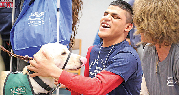 In this 2017 photo, Juan Garcia, a student at the Arizona State Schools for the Deaf and the Blind, pets a guide dog. (Photo courtesy Arizona State Schools for the Deaf and the Blind)