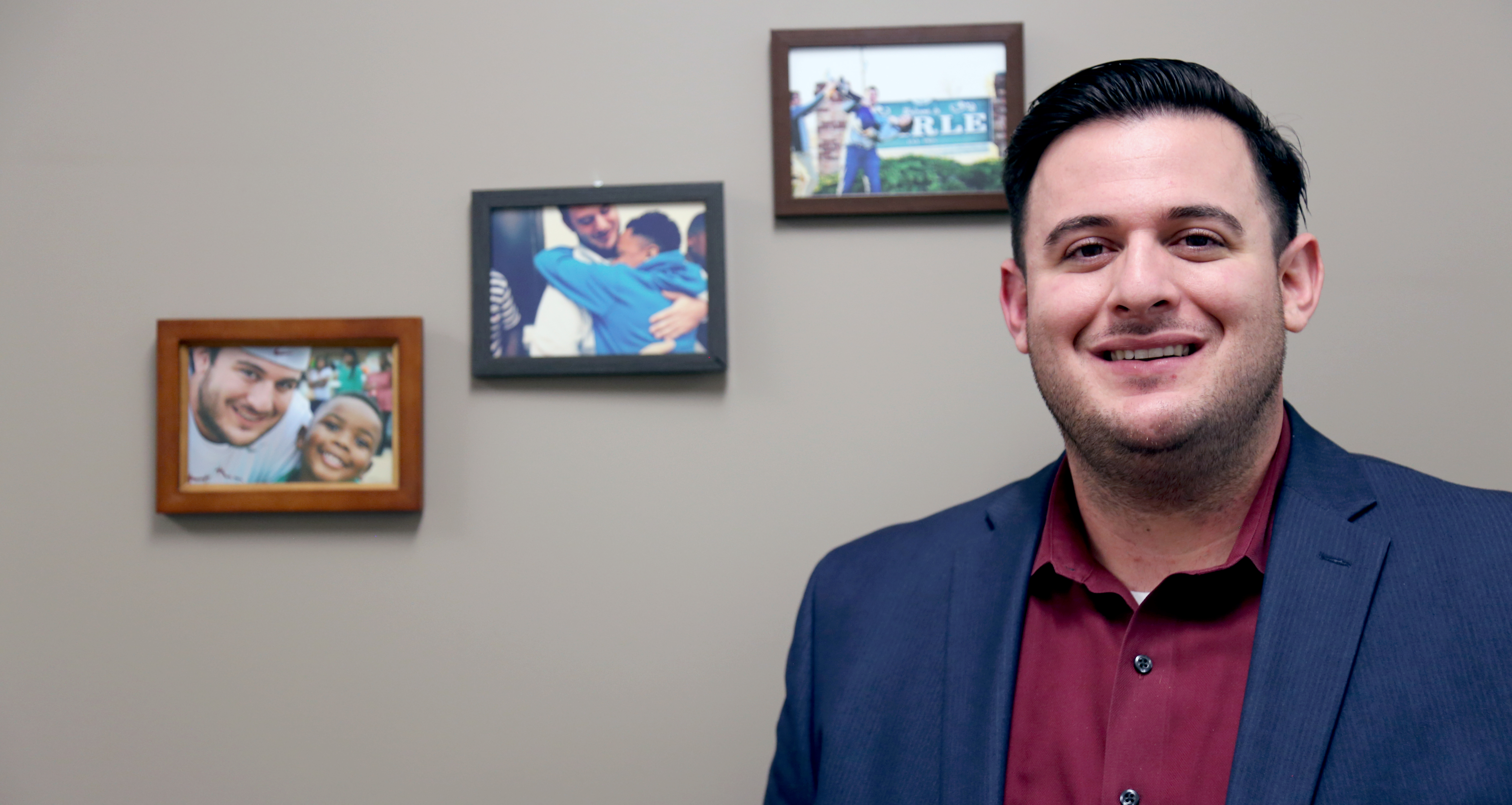 Matthew Simon stands beside photos of his former students in Arkansas. (Photo by Katie Campbell/Arizona Capitol Times)