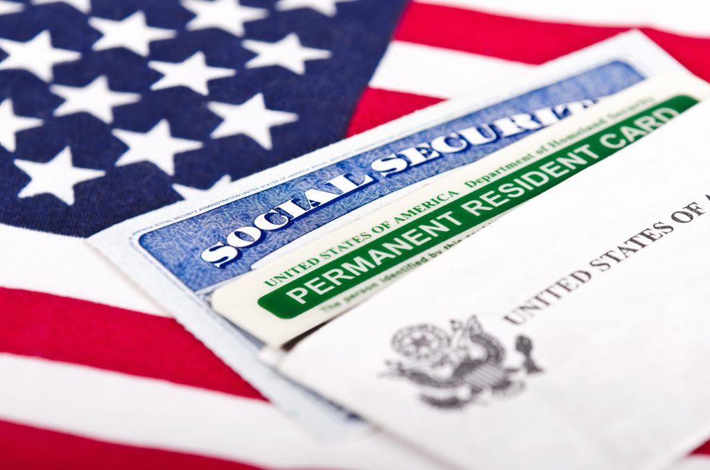 United States of America social security and green card with US flag on the background. Immigration concept. Closeup with shallow depth of field.